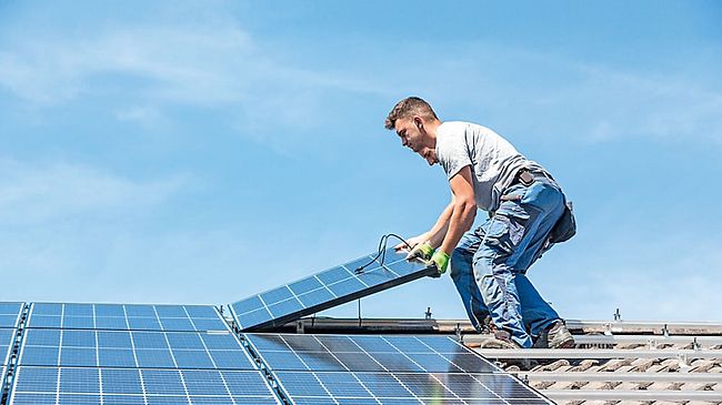 2 Arbeiter bringen ein Photovoltaik-Modul auf dem Dach an