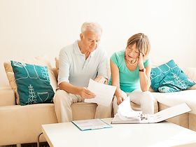 2 Senioren auf der Couch gucken sich Papiere an