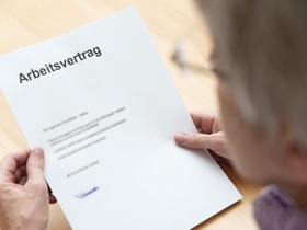 ältere Frau hält ihren Arbeitsvertrag in den Händen