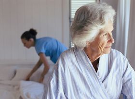 Ältere Frau und Pflegeperson beim Bettenmachen