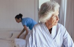 Ältere Frau und Pflegeperson beim Bettenmachen