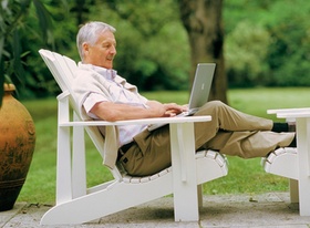 Älterer Herr mit Laptop im Garten