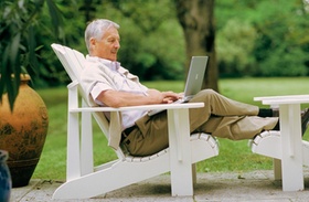 Älterer Herr mit Laptop im Garten