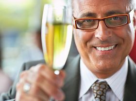 Älterer Mann prostet mit Sekt