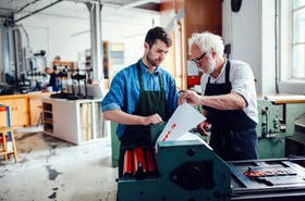 Älterer und jüngerer Mann Arbeiten zusammen an Druckmaschine