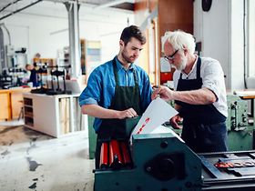 Älterer und jüngerer Mann Arbeiten zusammen an Druckmaschine
