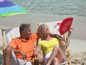 Aelteres Paar sitzt am Strand in Liegestuehlen