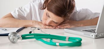 Ärztin mit Kopf auf dem Tisch