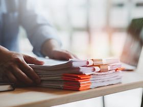 Schreibtisch Mann PC Akten Papierstapel