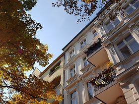 Altbau Mehrfamilienhaus mit Bäumen und Himmel
