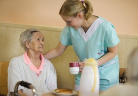 Altenheim, Pflegerin bringt Seniorin eine Tasse