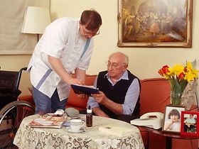 Altenpfleger zeigt aelterem Senior Unterlagen