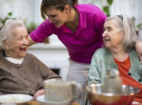 Altenpflegerin unterhält sich mit zwei älteren Frauen