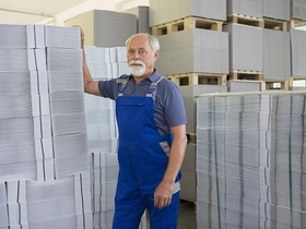 Alter Mann im Blaumann im Lager schaut in die Kamera