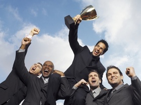 Anzugträger feiern mit Pokal unter blauem Himmel