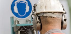 Arbeiter mit Schutzhelm vor Sicherheitshinweis