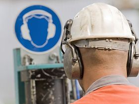 Arbeiter mit Schutzhelm vor Sicherheitshinweis