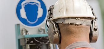 Arbeiter mit Schutzhelm vor Sicherheitshinweis