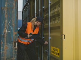 Arbeiterin mit Tablet überprüft Container