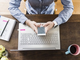 Arbeitsplatz von oben mit Laptop, Smartphone und Notizblock