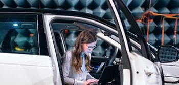 Autobau: Frau mit Laptop steigt aus Pkw