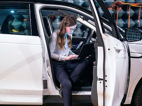 Autobau: Frau mit Laptop steigt aus Pkw