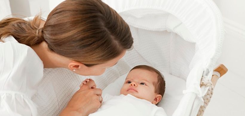 Baby in Wiege hält Finger der Mutter