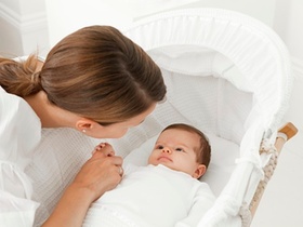 Baby in Wiege hält Finger der Mutter