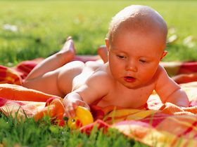 Baby liegt auf Decke in Wiese