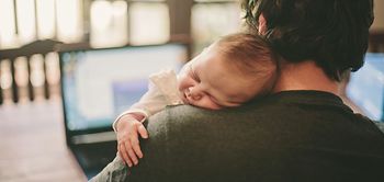 Baby schläft auf der Schulter von dem Vater