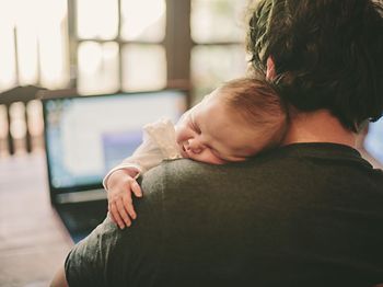 Baby schläft auf der Schulter von dem Vater