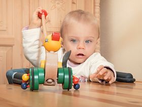 Baby sitzt mit Spielzeug am Tisch