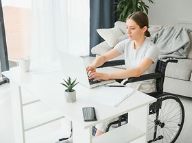 woman in a wheelchair works on the laptop PC in the home office 
