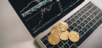 Bitcoin Münzen liegen auf Laptop