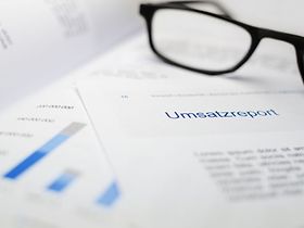Brille liegt auf Dokument mit Titel Umsatzreport