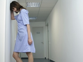 Brünette Frau in einem Klinikhemd auf dem Flur