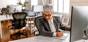 Mature businesswoman with short grey hair and eyeglasses working 