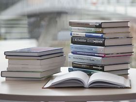 Bücher stapeln sich, ein Buch ist aufgeschlagen