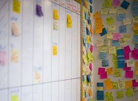 Bunte Notizzettel die an einer Wand und Whiteboard kleben