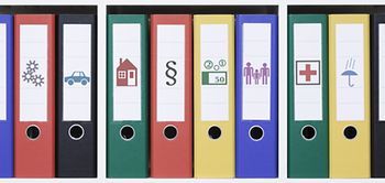 Bunte Ordner zu verschiedenen Themen im Regal stehend