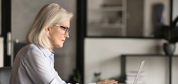 businessfrau 60 plus arbeitet fokussiert am laptop