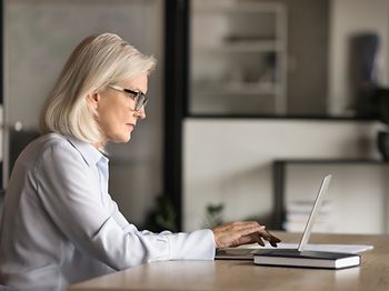 businessfrau 60 plus arbeitet fokussiert am laptop