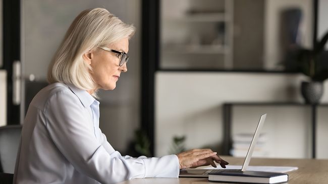 businessfrau 60 plus arbeitet fokussiert am laptop