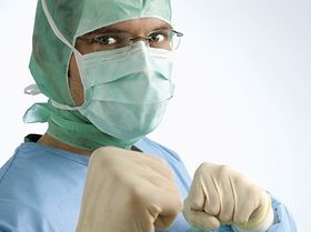 Chirurg mit Haube und Mundschutz, geballte Faeuste, Portraet