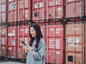 Young business woman using smartphone in industrial container yard