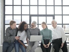 Divers zusammengestelltes Team schaut gemeinsam in einen Laptop
