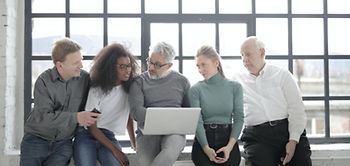 Divers zusammengestelltes Team schaut gemeinsam in einen Laptop