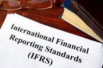 Dokument International Financial Reporting Standads auf Tisch mit Brille und Buch
