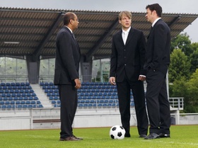 Drei Manager stehen auf Fussballplatz