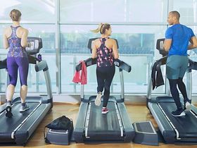 Drei Personen joggen auf Laufband in Fitnessstudio